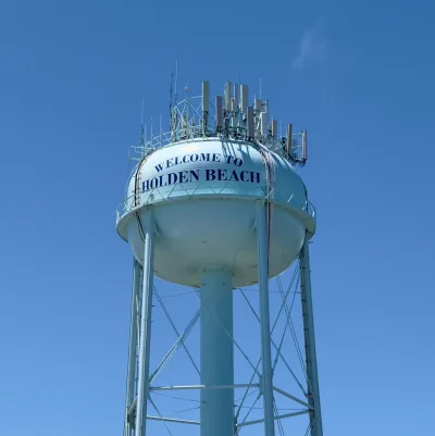 The Holden Beach water tower, painted "Welcome to Holden Beach", against a clear sky