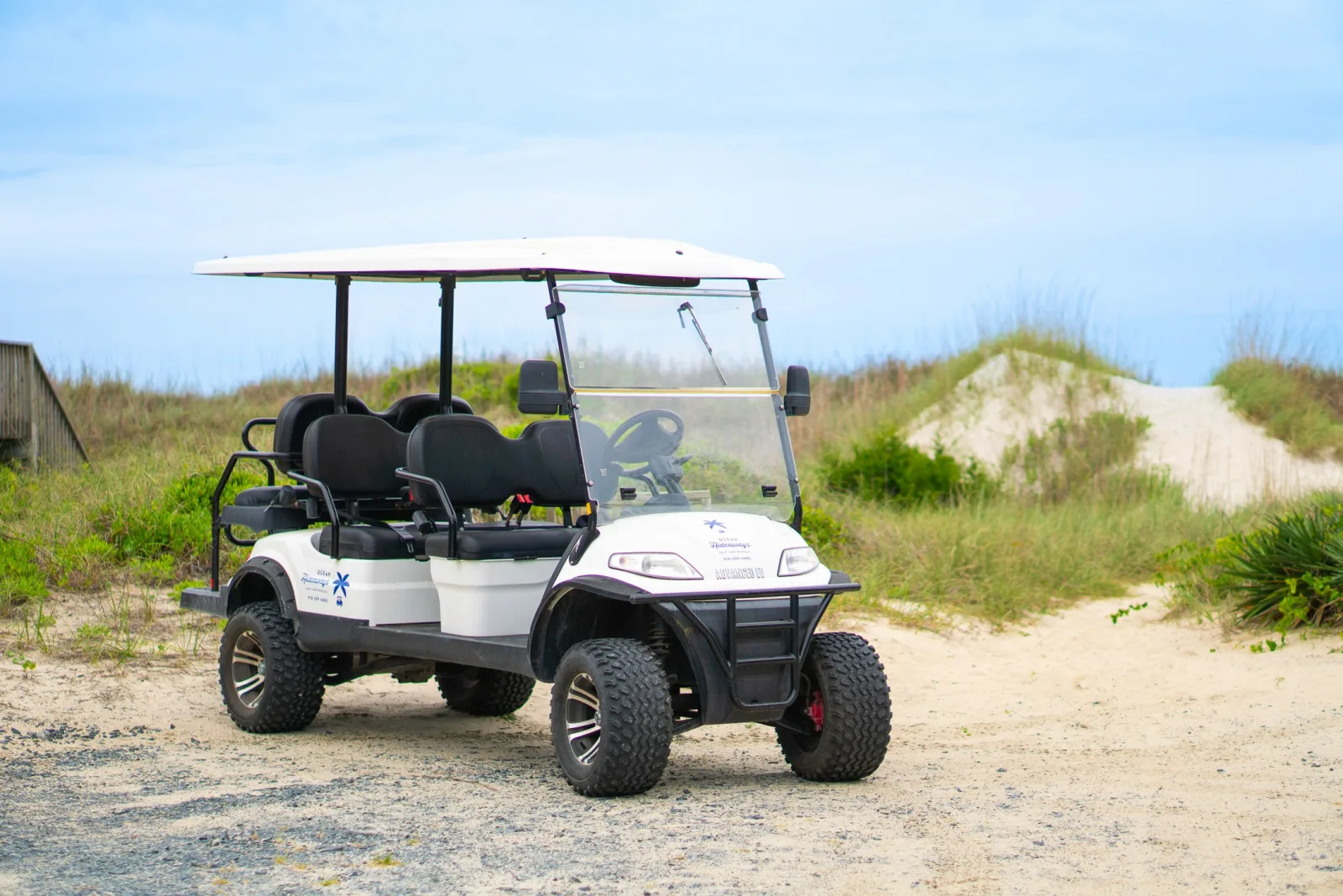 A white Ocean Hideaways golf cart parked at a coastal North Carolina beach house