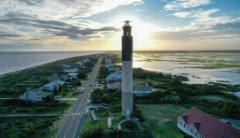 Oak Island lighthouse above the beach road at sunset