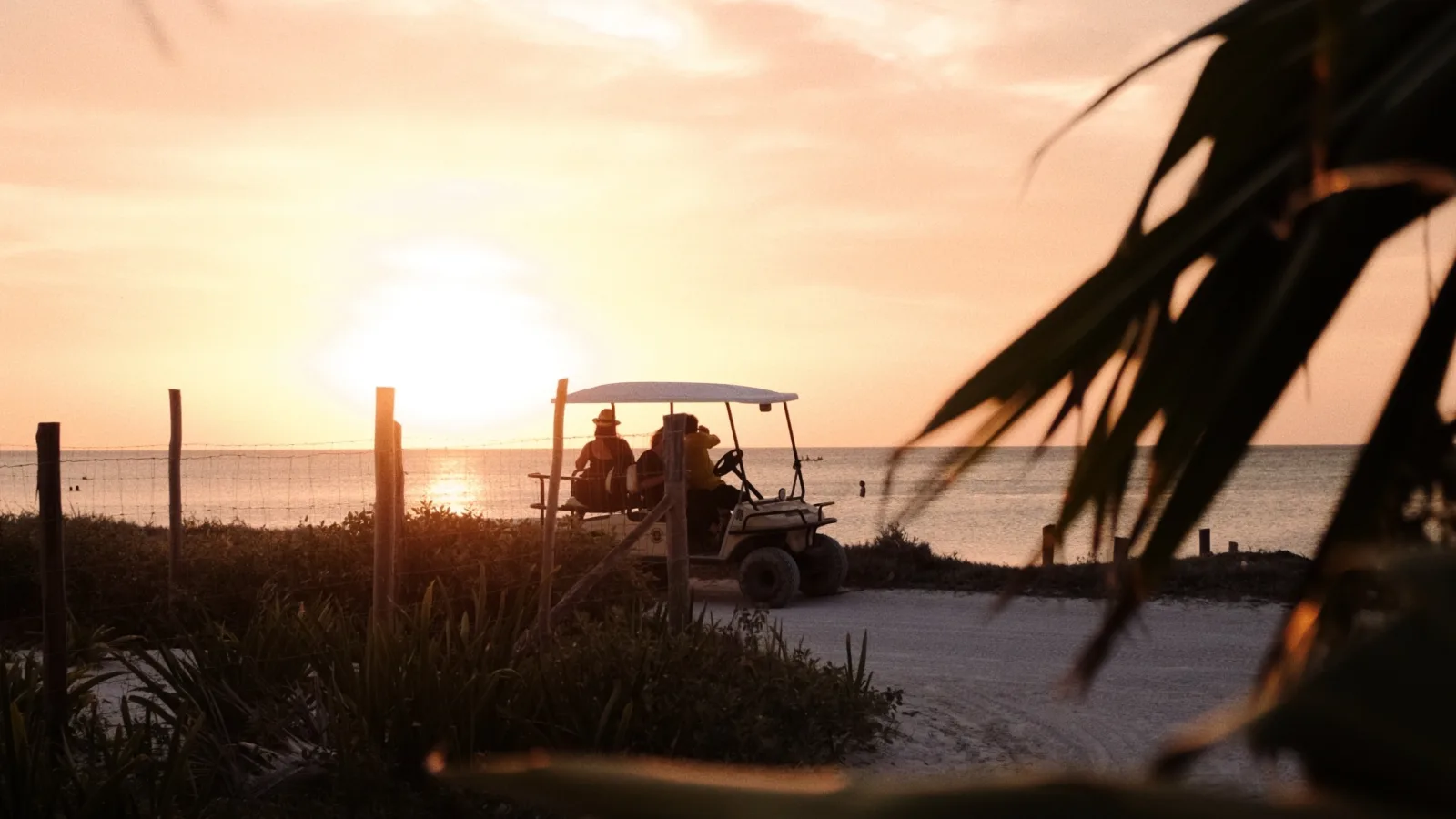 An Ocean Hideaways golf cart on a coastal road at golden hour